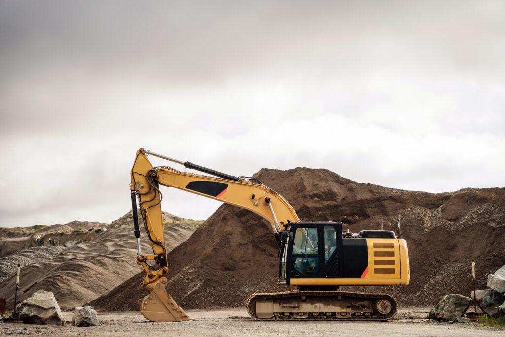 Yellow excavator near dirt mound
