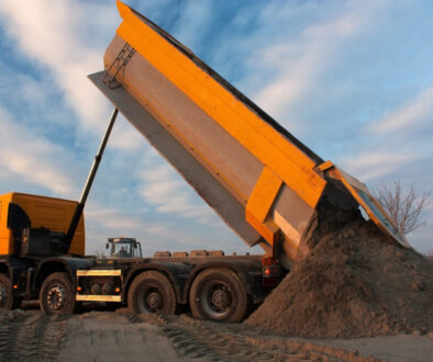 Dump truck unloading sand at sunset
