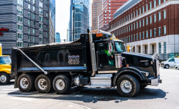 Black dump truck on city street