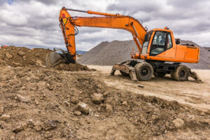 Excavator Types and Uses: Full Breakdown for Contractors 2 orange wheeled excavator in brown dirt and rocks