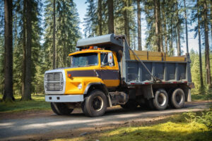 Yellow dump truck in forest setting