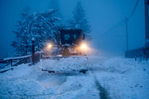 Snow plow with lights clearing a snowy road