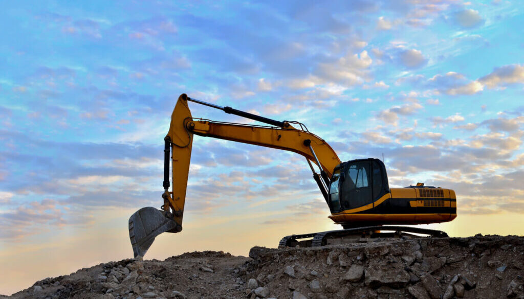 Construction Equipment Excavator at sunrise on hill