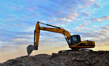 Construction Equipment Excavator at sunrise on hill