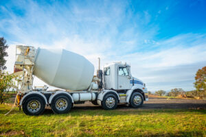 White cement truck on grassy field