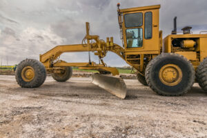Yellow motor grader on gravel road