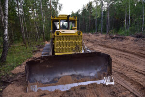 Yellow bulldozer on sandy forest path