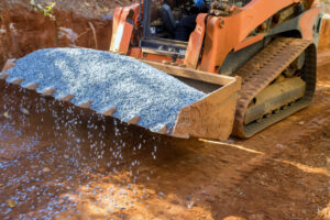 Skid steer dumping gravel on ground